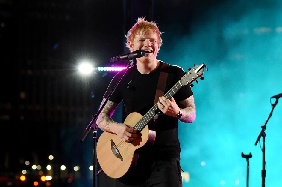 Ed Sheeran performing an acoustic tribute song live on stage.
